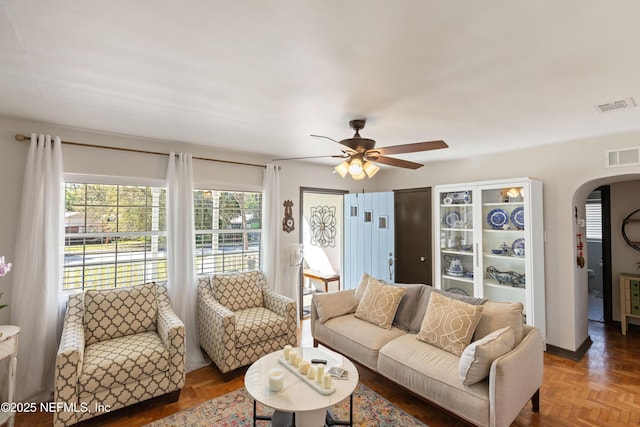 living room featuring a ceiling fan, arched walkways, and visible vents