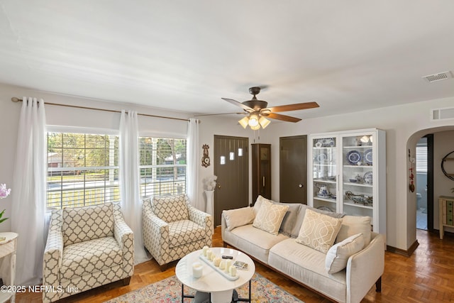 living room with visible vents, arched walkways, and a ceiling fan