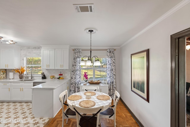 dining room with an inviting chandelier, crown molding, baseboards, and visible vents