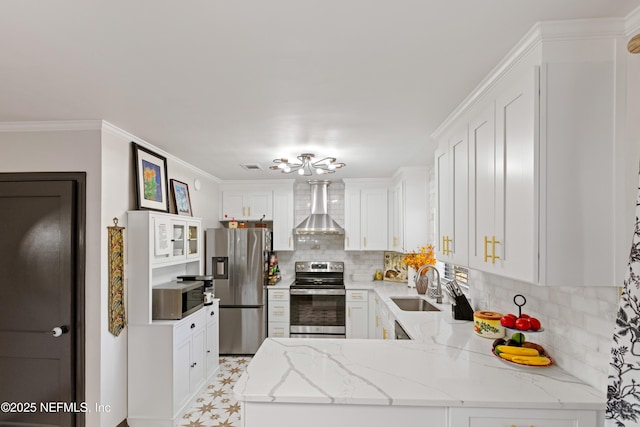 kitchen featuring ornamental molding, a sink, a peninsula, appliances with stainless steel finishes, and wall chimney exhaust hood