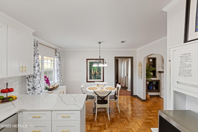 kitchen with crown molding, hanging light fixtures, an inviting chandelier, arched walkways, and white cabinetry