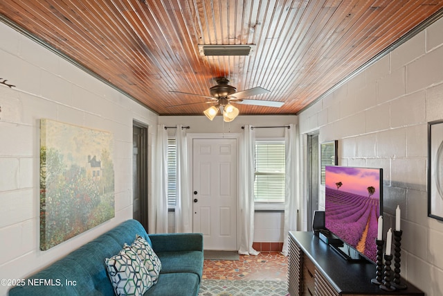 interior space with wooden ceiling, concrete block wall, a ceiling fan, and visible vents