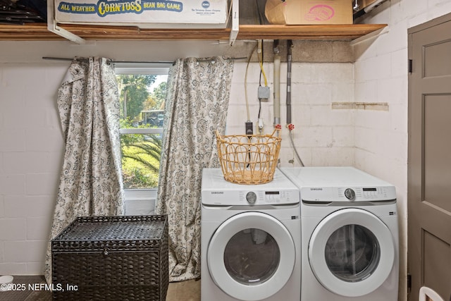 clothes washing area featuring plenty of natural light, concrete block wall, and separate washer and dryer