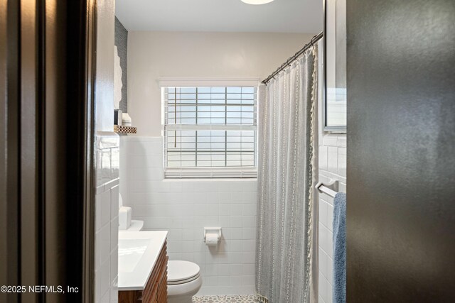 full bathroom featuring curtained shower, tile walls, toilet, wainscoting, and vanity