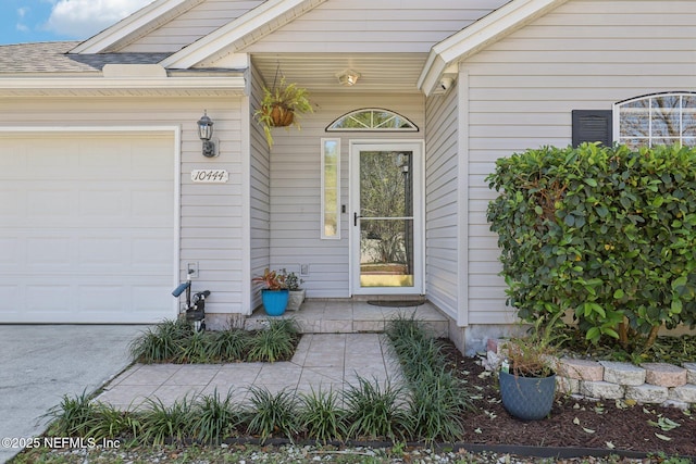 entrance to property featuring an attached garage and roof with shingles