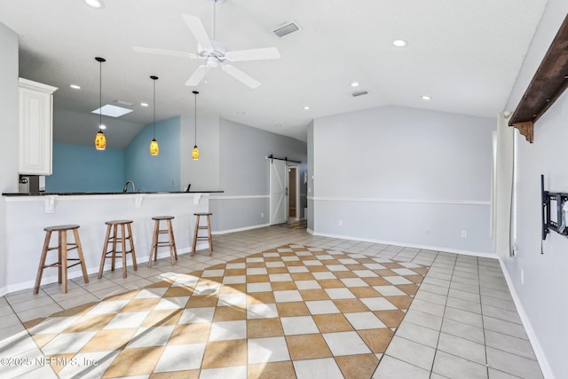 kitchen with a barn door, a kitchen breakfast bar, lofted ceiling, and light tile patterned flooring