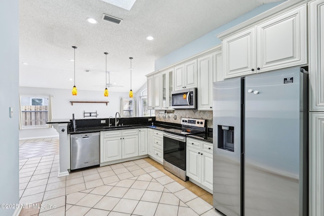 kitchen with visible vents, a sink, dark countertops, appliances with stainless steel finishes, and a peninsula