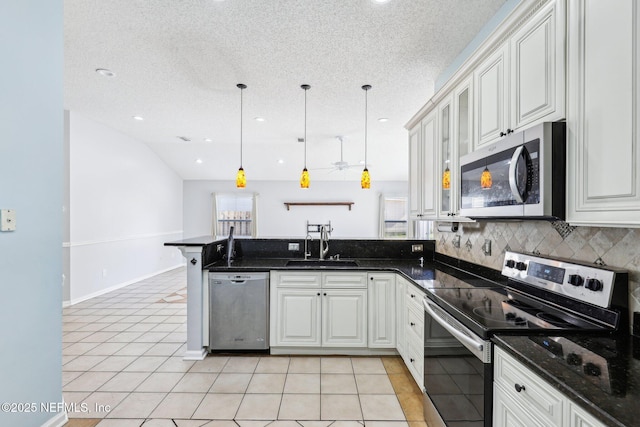 kitchen with a sink, a peninsula, light tile patterned flooring, and stainless steel appliances