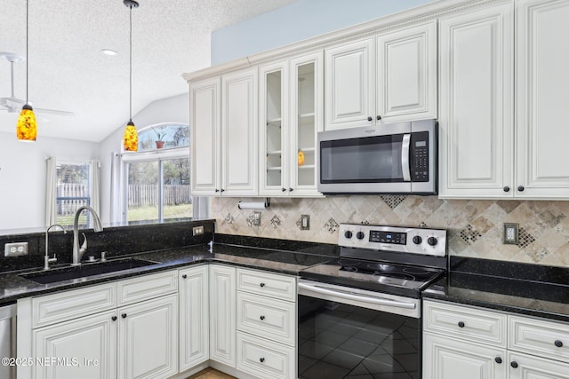 kitchen featuring pendant lighting, a sink, a textured ceiling, appliances with stainless steel finishes, and vaulted ceiling