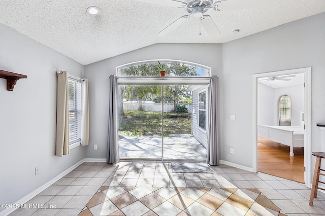 interior space with light tile patterned floors, a textured ceiling, lofted ceiling, and ceiling fan