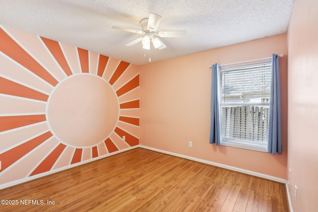 spare room featuring ceiling fan, wood finished floors, baseboards, and a textured ceiling