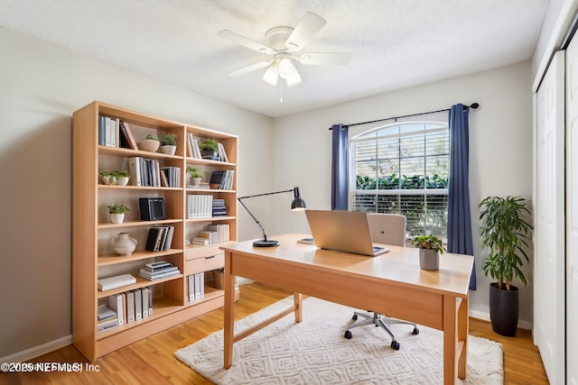 home office with a ceiling fan, baseboards, and light wood finished floors