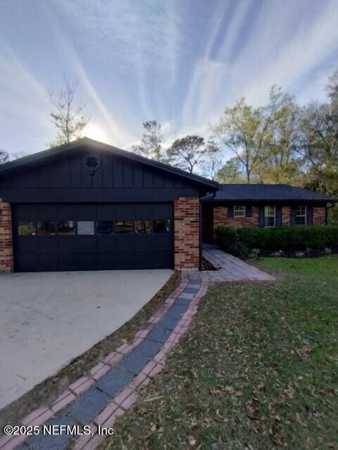 view of front of home featuring a front yard, an attached garage, brick siding, and driveway