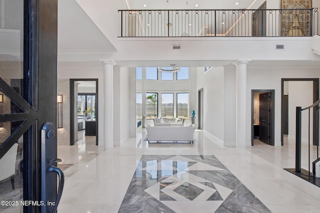 foyer entrance with visible vents, marble finish floor, and decorative columns