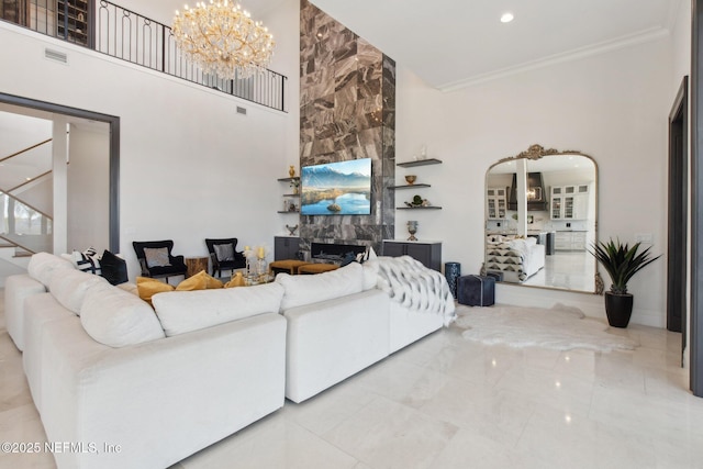 living room featuring an inviting chandelier, a high ceiling, arched walkways, ornamental molding, and a large fireplace