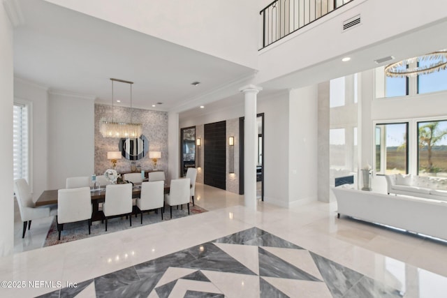 dining space featuring marble finish floor, crown molding, an inviting chandelier, and an accent wall