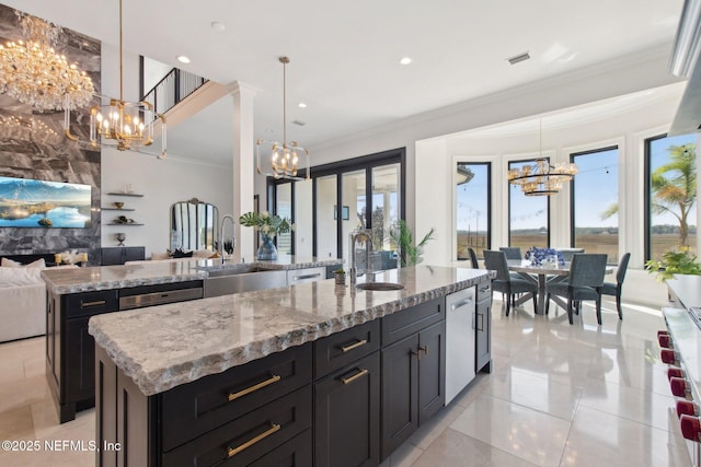 kitchen featuring a sink, open floor plan, an inviting chandelier, and a kitchen island with sink