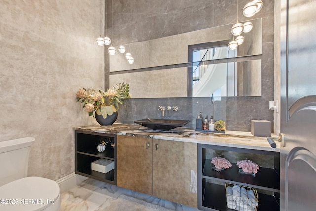 bathroom featuring decorative backsplash, toilet, vanity, and marble finish floor