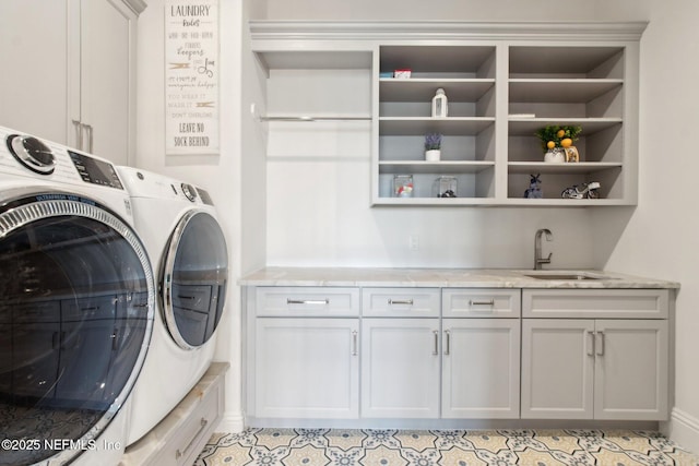 clothes washing area featuring washing machine and clothes dryer, cabinet space, and a sink