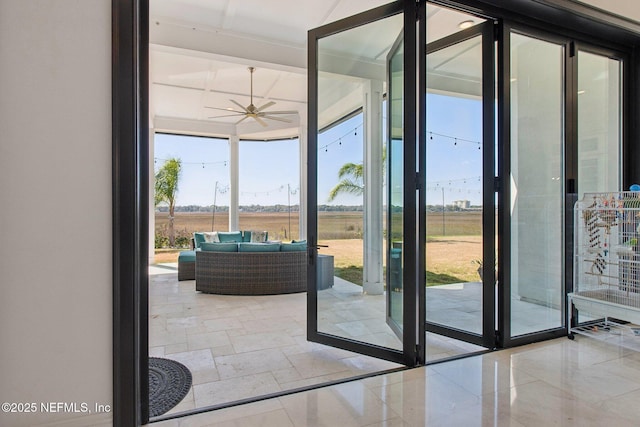doorway with a wealth of natural light, ceiling fan, and expansive windows