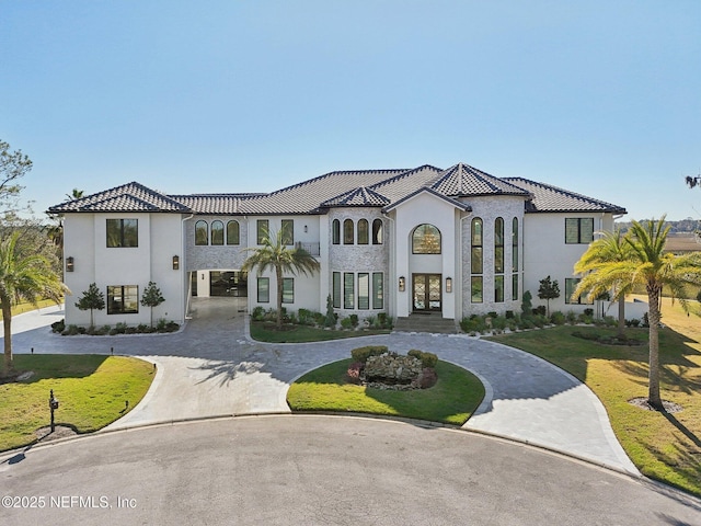mediterranean / spanish house with curved driveway, french doors, a front yard, and stucco siding