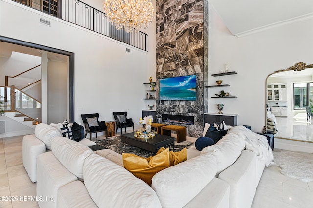 living area featuring a high end fireplace, tile patterned flooring, stairway, a high ceiling, and an inviting chandelier