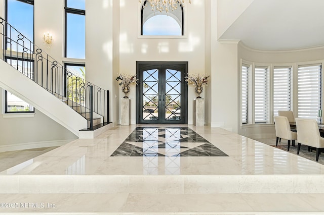 entryway with stairway, marble finish floor, and a high ceiling