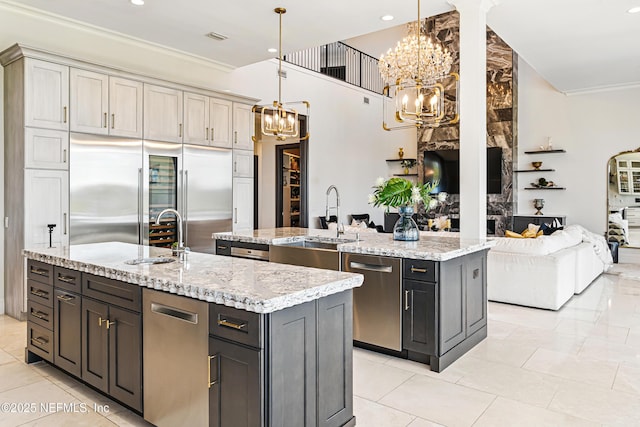 kitchen with a sink, a kitchen island with sink, stainless steel appliances, and a chandelier