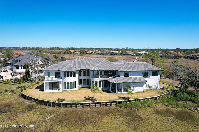 exterior space with a balcony, a tiled roof, a fenced backyard, and a lawn