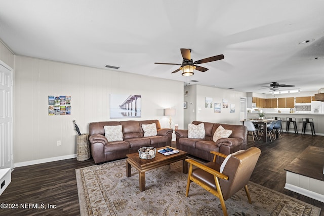 living room featuring visible vents, baseboards, dark wood finished floors, and a ceiling fan