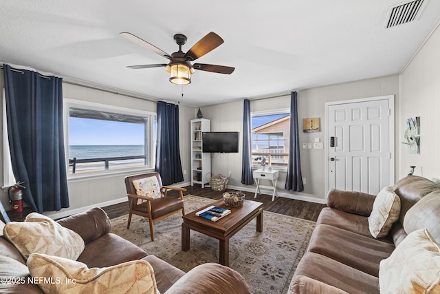 living area with visible vents, baseboards, wood finished floors, and a ceiling fan