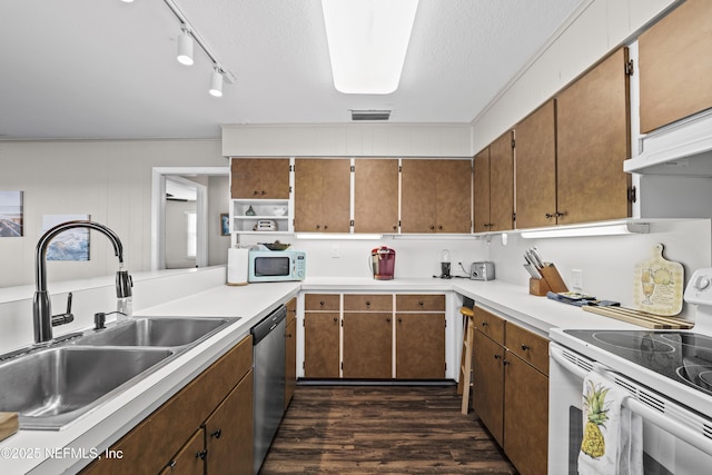 kitchen with dark wood-type flooring, a sink, a textured ceiling, white appliances, and light countertops