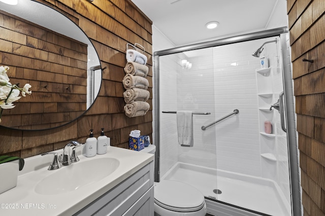 full bath with a shower stall, toilet, vanity, and wood walls