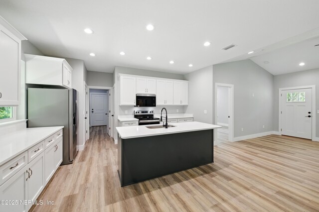 207 Palmetto Ave N, Florahome, FL 32140 - kitchen featuring appliances with stainless steel finishes, a sink, a center island with sink, light wood finished floors, and light countertops