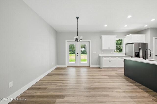 207 Palmetto Ave N, Florahome, FL 32140 - kitchen with stainless steel refrigerator with ice dispenser, light countertops, a chandelier, baseboards, and white cabinetry