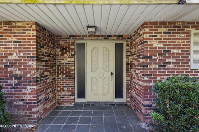 view of exterior entry featuring brick siding