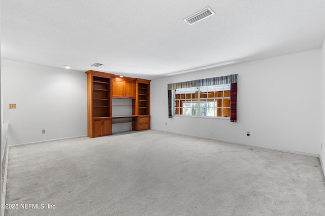 unfurnished living room with visible vents, light colored carpet, and baseboards