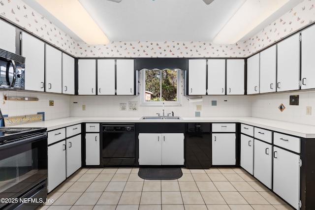 kitchen with a sink, black appliances, light countertops, and light tile patterned floors