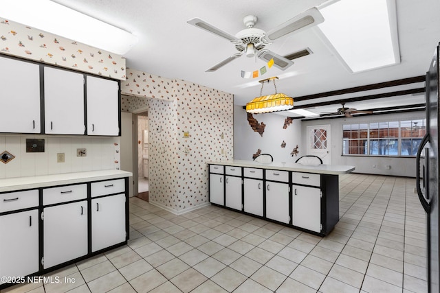 kitchen with wallpapered walls, light countertops, and ceiling fan