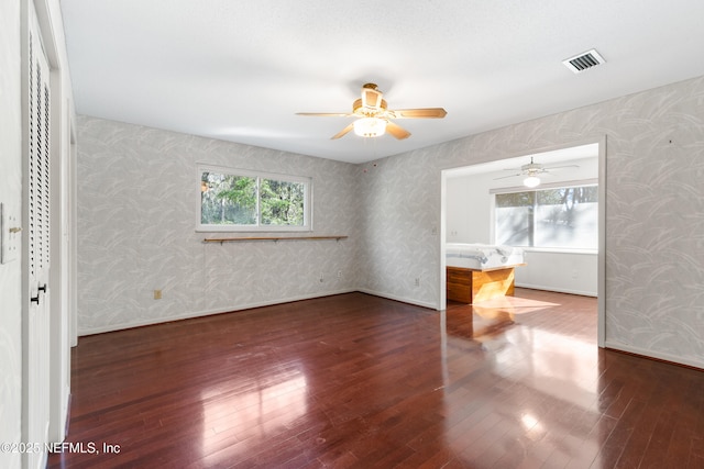 spare room with visible vents, wallpapered walls, ceiling fan, and hardwood / wood-style floors