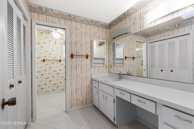 bathroom featuring tile patterned floors, wallpapered walls, baseboards, a closet, and vanity