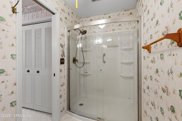 bathroom featuring a closet, a stall shower, and wallpapered walls