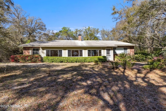 ranch-style house featuring metal roof and a chimney