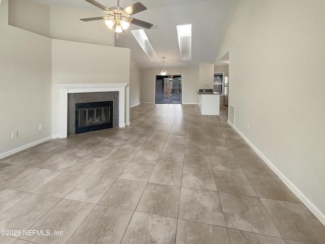 unfurnished living room featuring a fireplace, light tile patterned floors, a ceiling fan, and baseboards