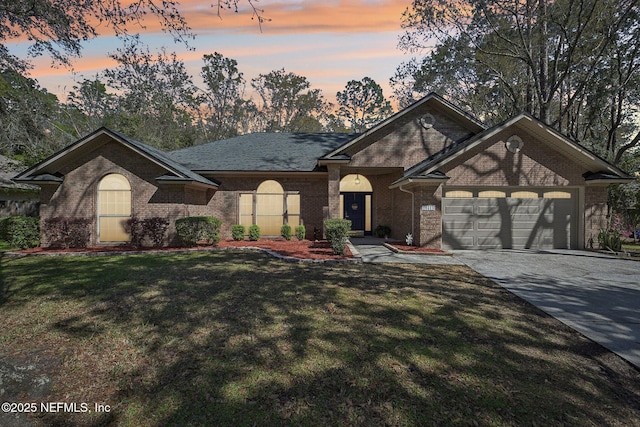 view of front of property featuring brick siding, a shingled roof, a front yard, driveway, and an attached garage