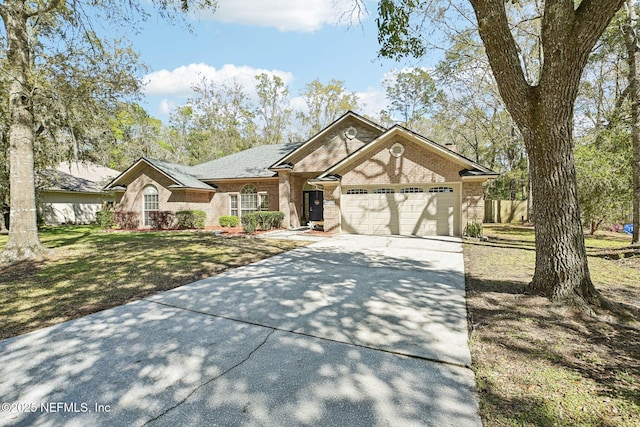 ranch-style house featuring concrete driveway, an attached garage, brick siding, and a front yard