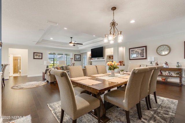 dining area featuring a raised ceiling, recessed lighting, dark wood-style flooring, and ornamental molding