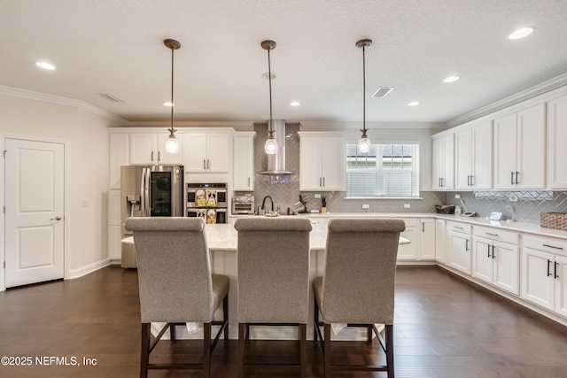 kitchen featuring visible vents, stainless steel appliances, ornamental molding, light countertops, and wall chimney range hood