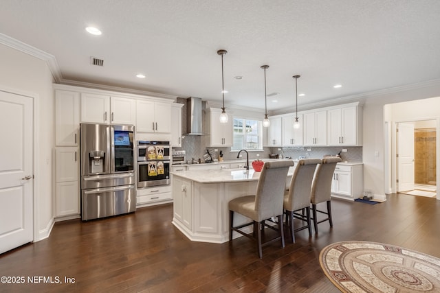 kitchen with white cabinets, appliances with stainless steel finishes, dark wood-type flooring, and wall chimney range hood