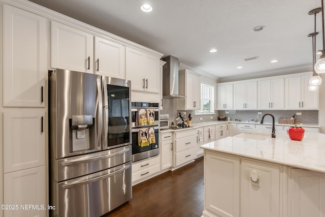 kitchen with a sink, decorative backsplash, stainless steel appliances, white cabinetry, and wall chimney exhaust hood